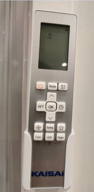 Pilot do klimatyzacji marki Kaisai zamocowany w uchwycie ściennym, wyświetlacz pokazuje tryb chłodzenia.