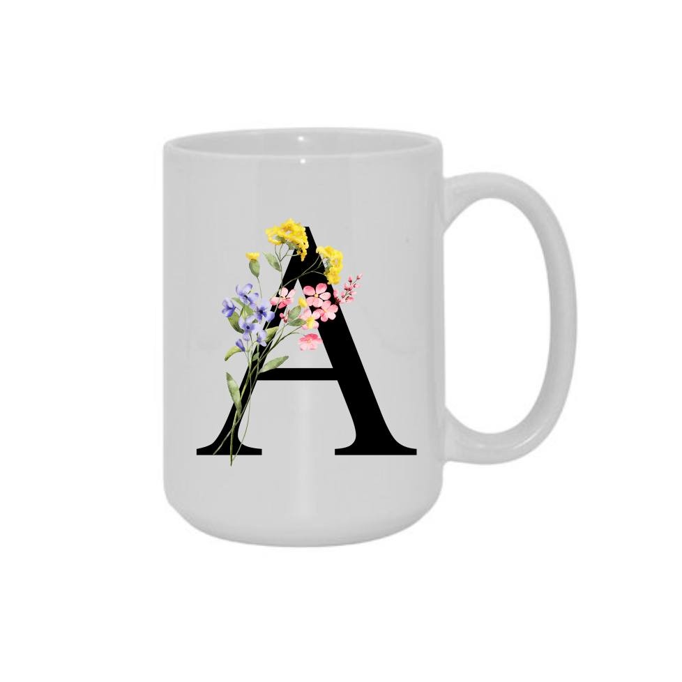 Biały kubek z czarną literą A ozdobioną akwarelowymi kwiatami w odcieniach żółci, fioletu i różu na białym tle.