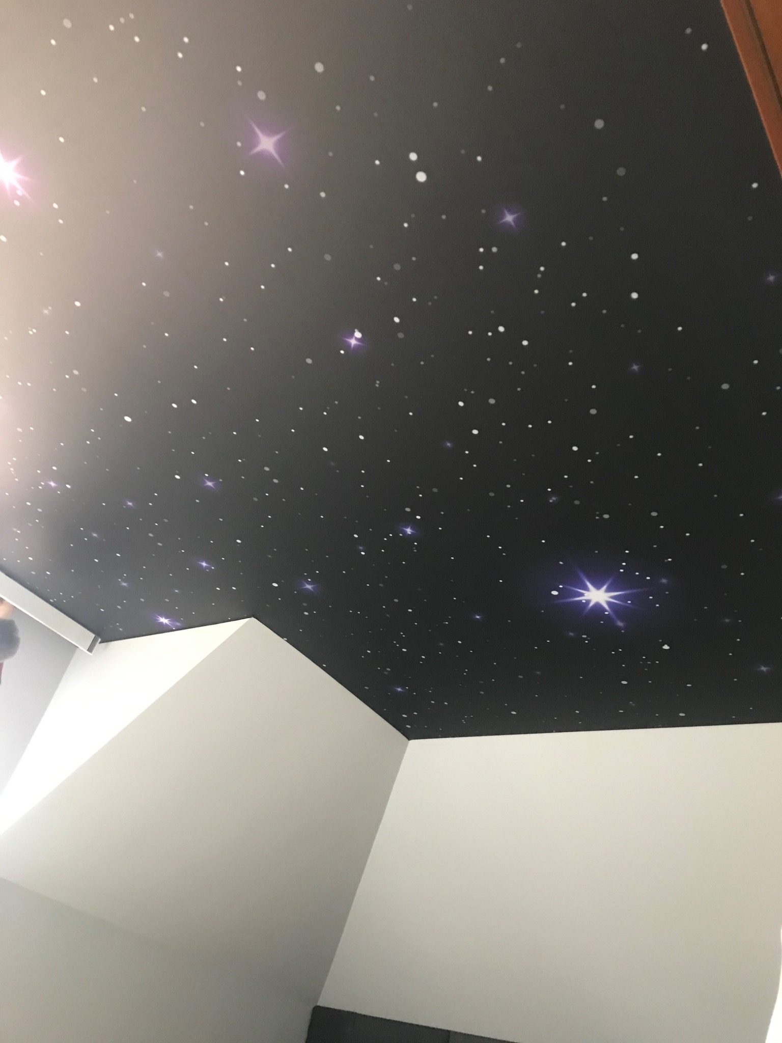 Czarny sufit z motywem kosmosu, białe ściany, widok z dołu.