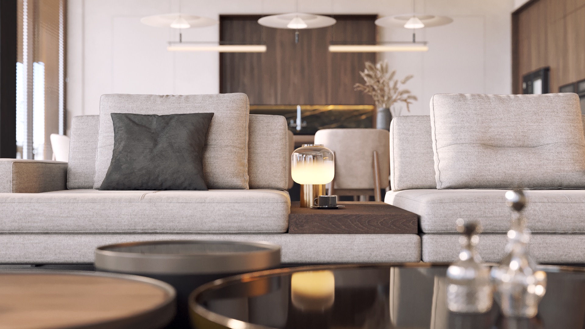 Nowoczesny salon: jasnoszara sofa z ciemnoszarą poduszką, lampka nocna na drewnianym stoliku, szklany stolik kawowy z dekoracyjnymi buteleczkami, minimalistyczne oświetlenie sufitowe.