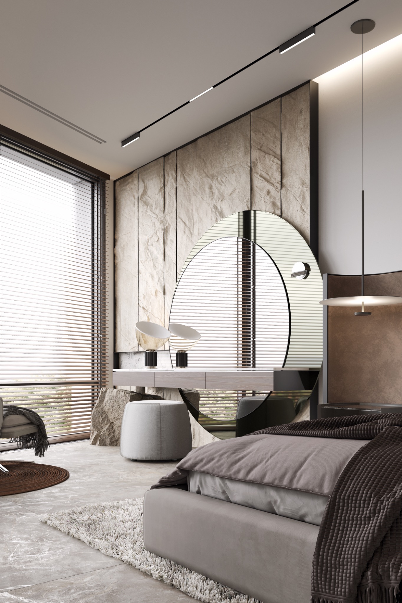 Nowoczesna sypialnia z łóżkiem w odcieniach szarości, okrągłym lustrem nad toaletką z kamiennym blatem i lampami stołowymi, oraz kamienną ścianą za lustrem.