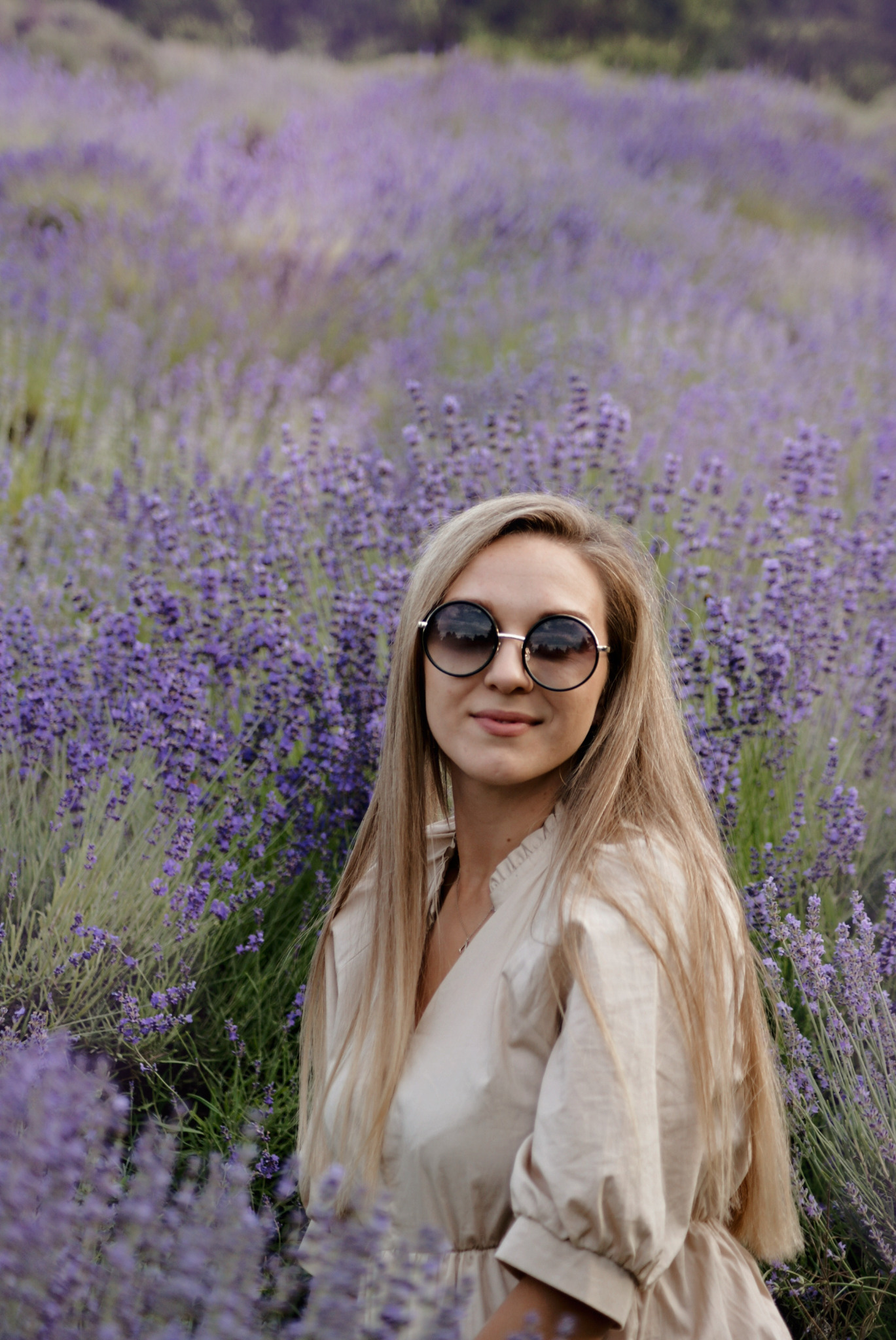 Portret kobiety w okularach przeciwsłonecznych na tle kwitnącego pola lawendy, z delikatnym oświetleniem i miękkimi cieniami.