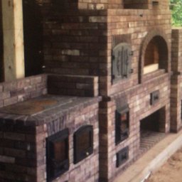 Bau-Remo usługi remontowo budowlane - Murowana konstrukcja z cegły, przypominająca piec chlebowy lub wędzarnię, z drewnianą konstrukcją podtrzymującą, jeszcze w trakcie budowy, z widocznymi drzwiczkami.
