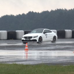 Tryb Manualny by Jakub Szołdra-Laszczyk - Biały samochód sportowy Mercedes-AMG z numerem 9 na mokrym torze, opony w tle, deszczowa pogoda.