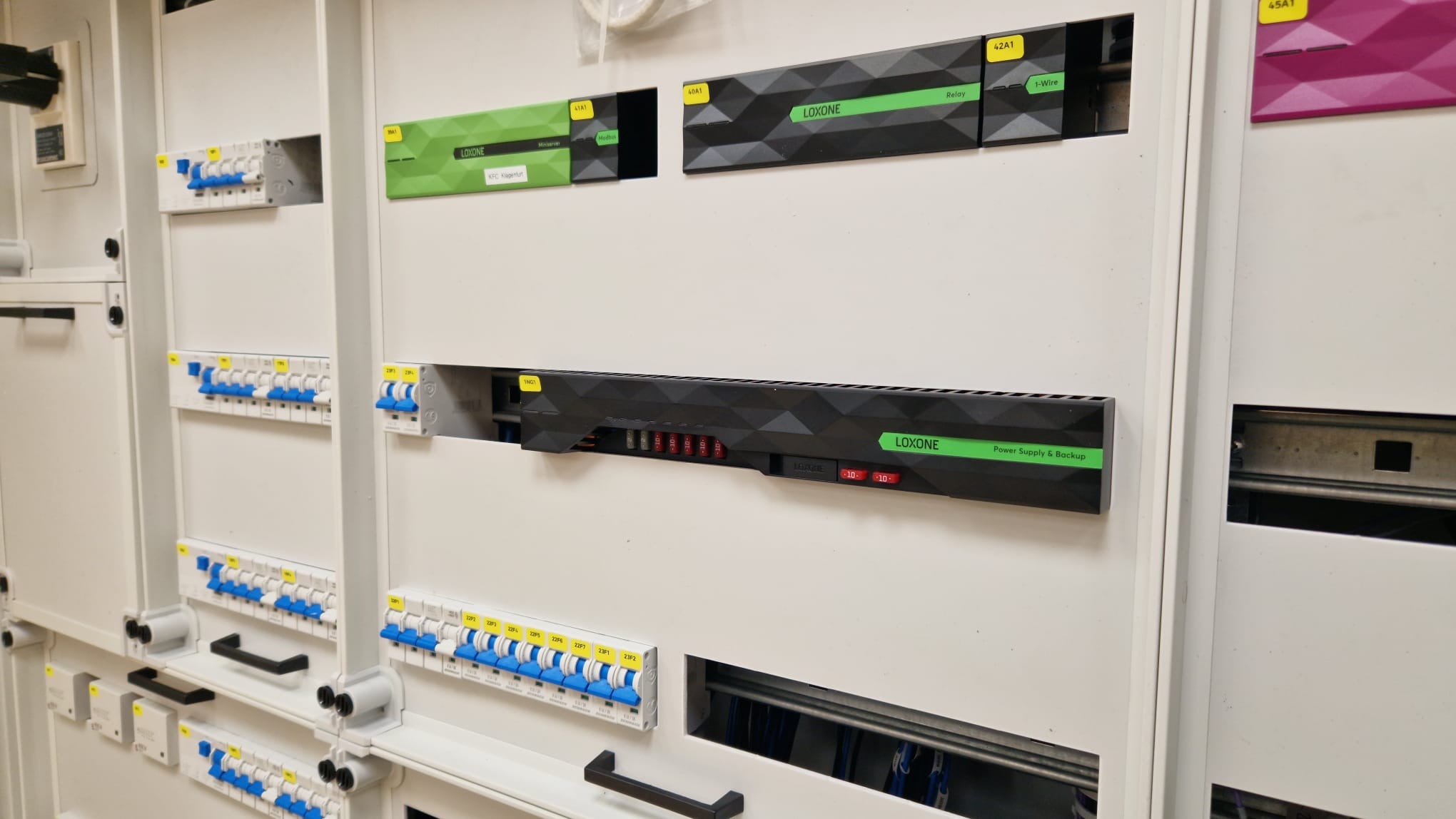 Rozdzielnica elektryczna z modułami Loxone, widoczne zabezpieczenia nadprądowe i moduły sterujące, zainstalowane w metalowej szafie.