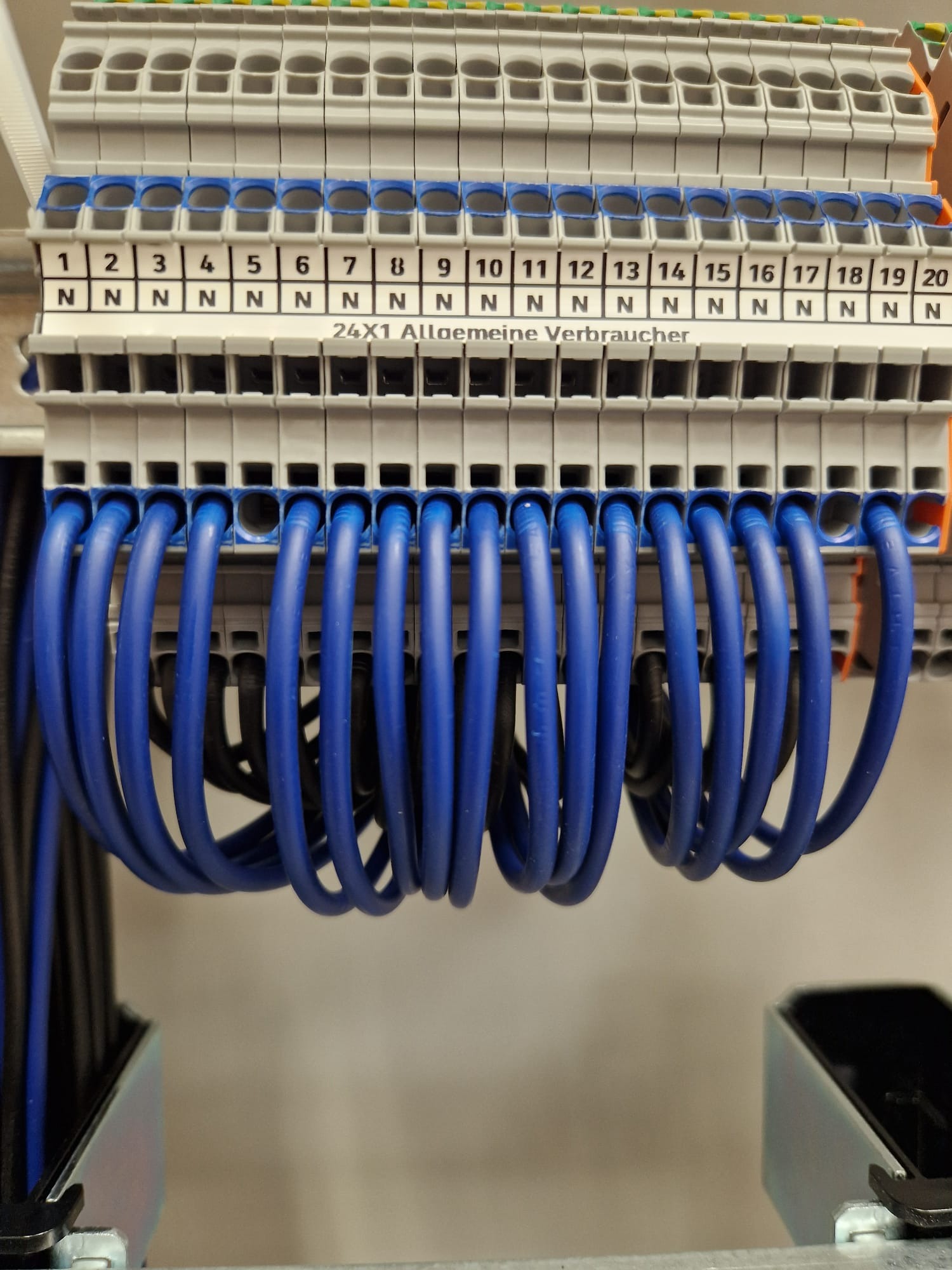 Szereg złączek elektrycznych z podłączonymi przewodami w kolorze niebieskim i czarnym, widoczne oznaczenia numerów złączek.