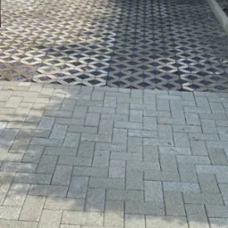 Dwa rodzaje nawierzchni: ażurowa z wypełnieniem żwirowym i klasyczna z prostokątnych szarych kostek, oddzielone betonową obwódką.