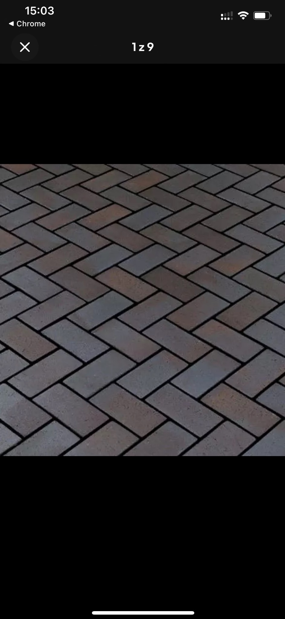 Ułożona kostka brukowa w odcieniach brązu i szarości, wzór jodełki, widok z góry.