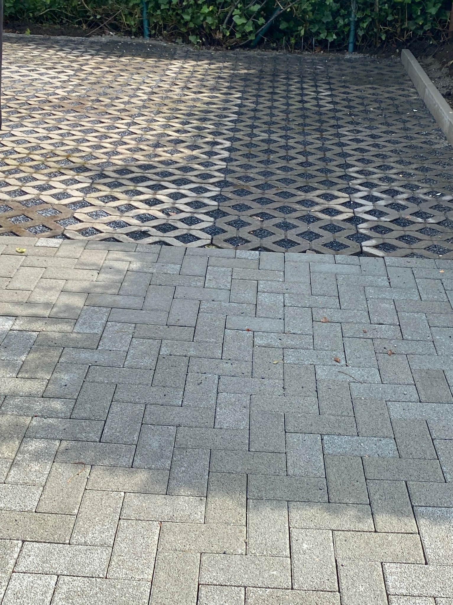 Dwa rodzaje nawierzchni: ażurowa z wypełnieniem żwirowym i klasyczna z prostokątnych szarych kostek, oddzielone betonową obwódką.