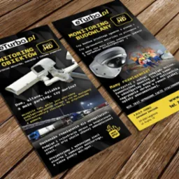 Dwie ulotki DL na drewnianym tle prezentujące ofertę monitoringu wizyjnego eTurbo.pl, z ilustracjami kamer i tekstem o monitoringu obiektów, budowlanych i terenów otwartych.