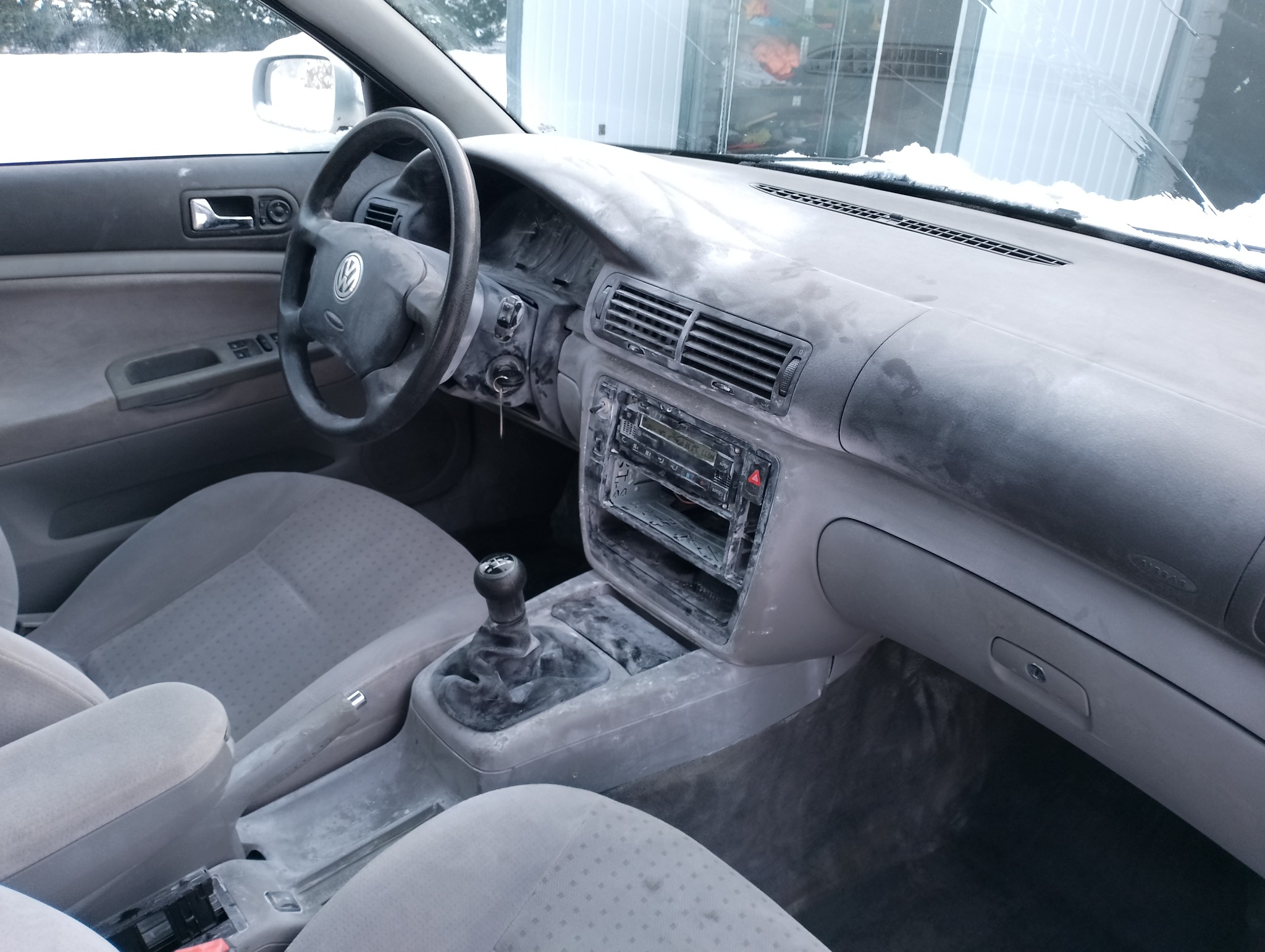 Wnętrze samochodu Volkswagen Passat B5 pokryte grubą warstwą białego proszku, widoczne fotele, deska rozdzielcza, kierownica i dźwignia zmiany biegów. Ślady proszku również na szybie i karoserii...