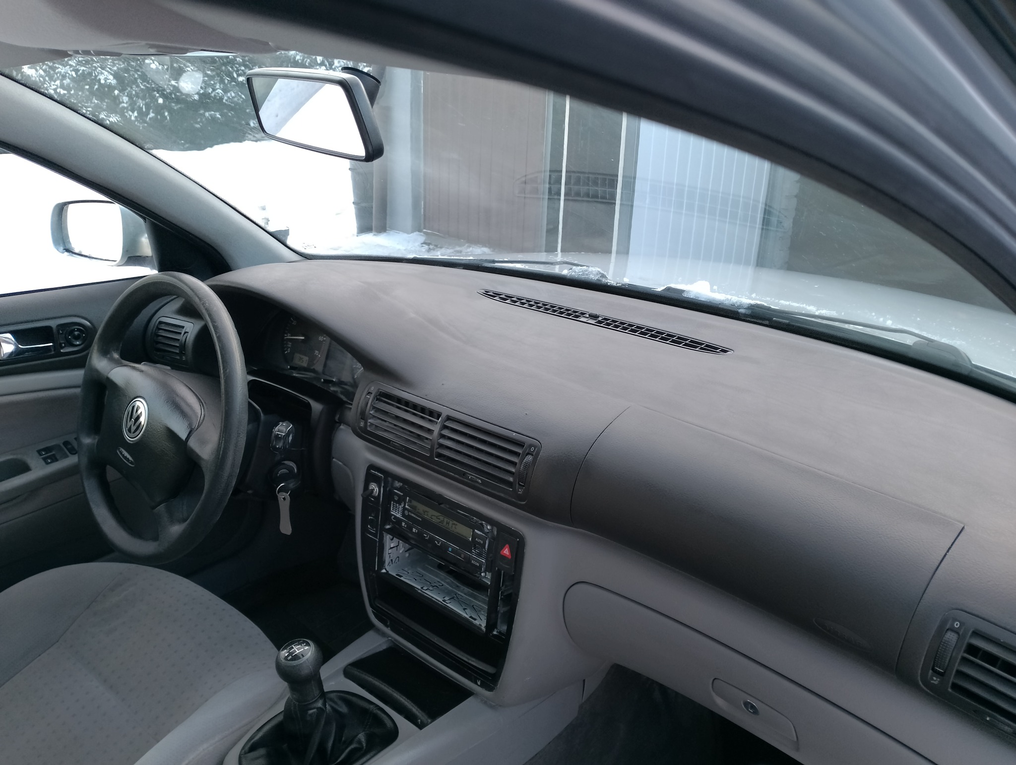 Wnętrze samochodu Volkswagen Passat B5 z widoczną deską rozdzielczą, kierownicą z logo VW oraz fragmentem fotela kierowcy; za szybą przednią widoczny ośnieżony krajobraz.