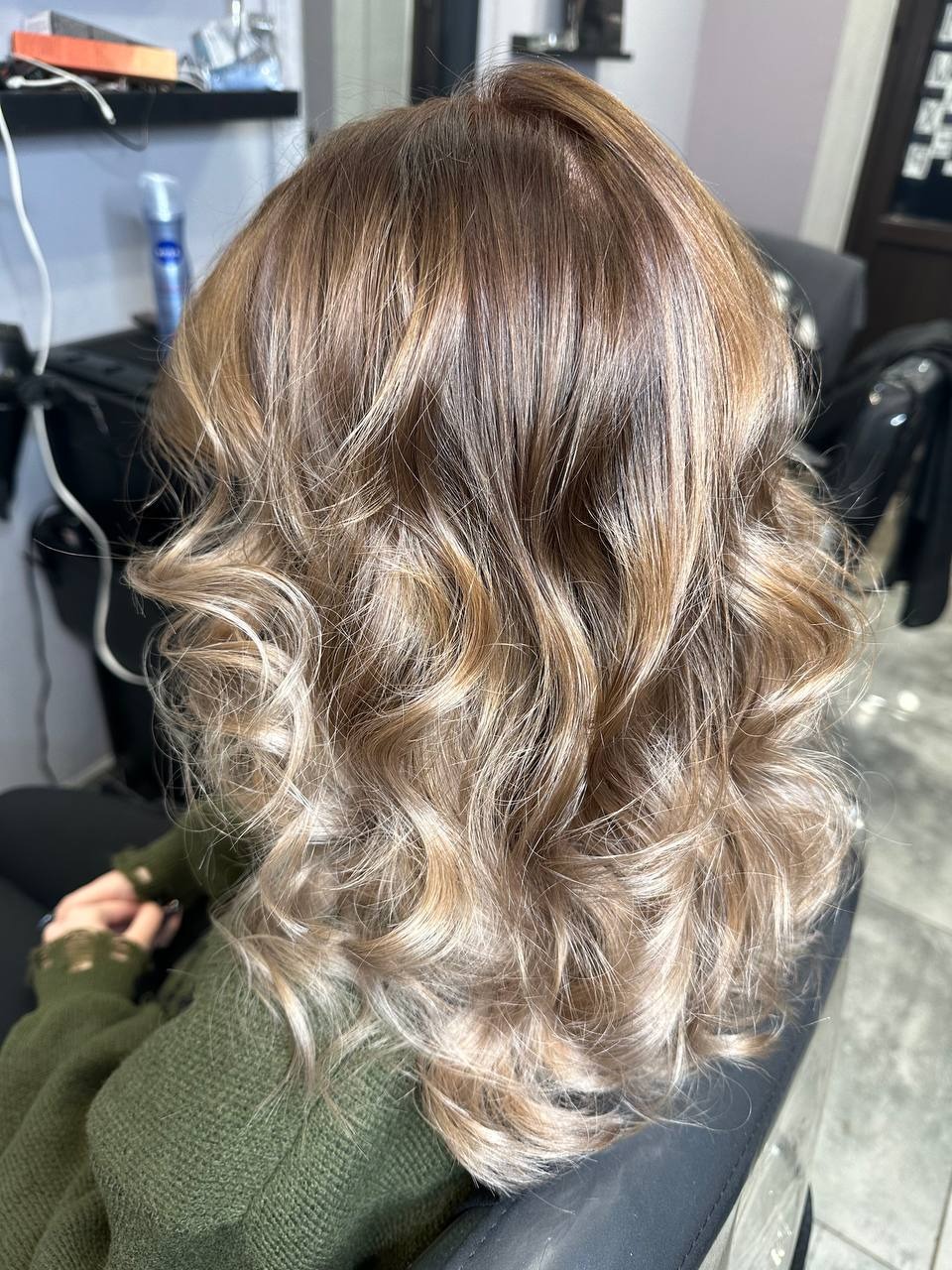Włosy po koloryzacji sombre z delikatnymi falami, widoczne z tyłu, na tle salonu.