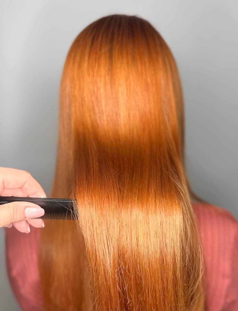 Długie, proste, miedziane włosy czesane czarnym grzebieniem, widok z tyłu, oświetlenie studyjne.