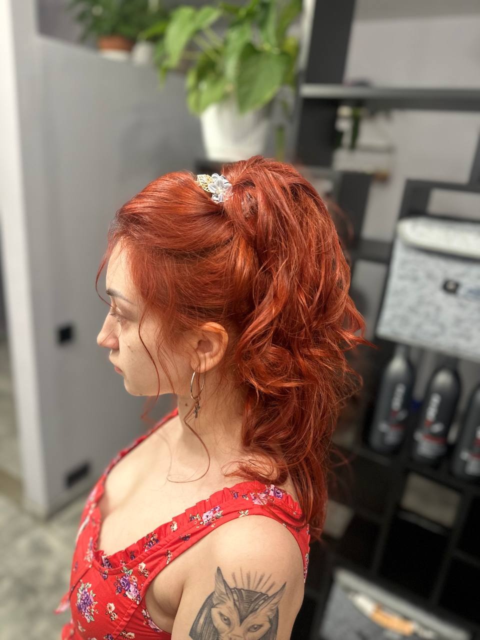Rude włosy upięte w wysoki kucyk z ozdobną spinką, widok z profilu, tatuaż na ramieniu.