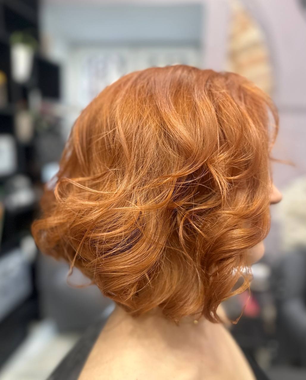 Krótkie, miedziane, falowane włosy po stylizacji, widok z profilu, delikatny makijaż.