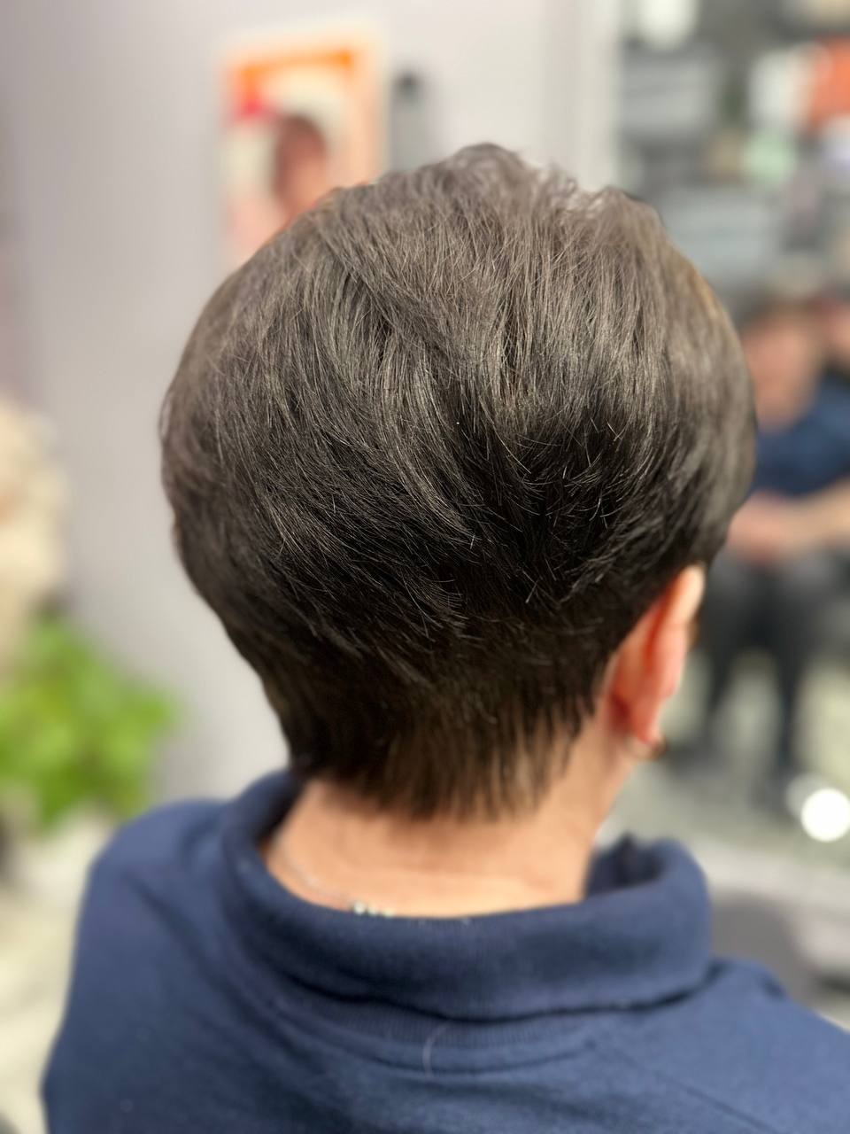 Krótkie, ciemne włosy po strzyżeniu, widok z tyłu, subtelne refleksy światła.
