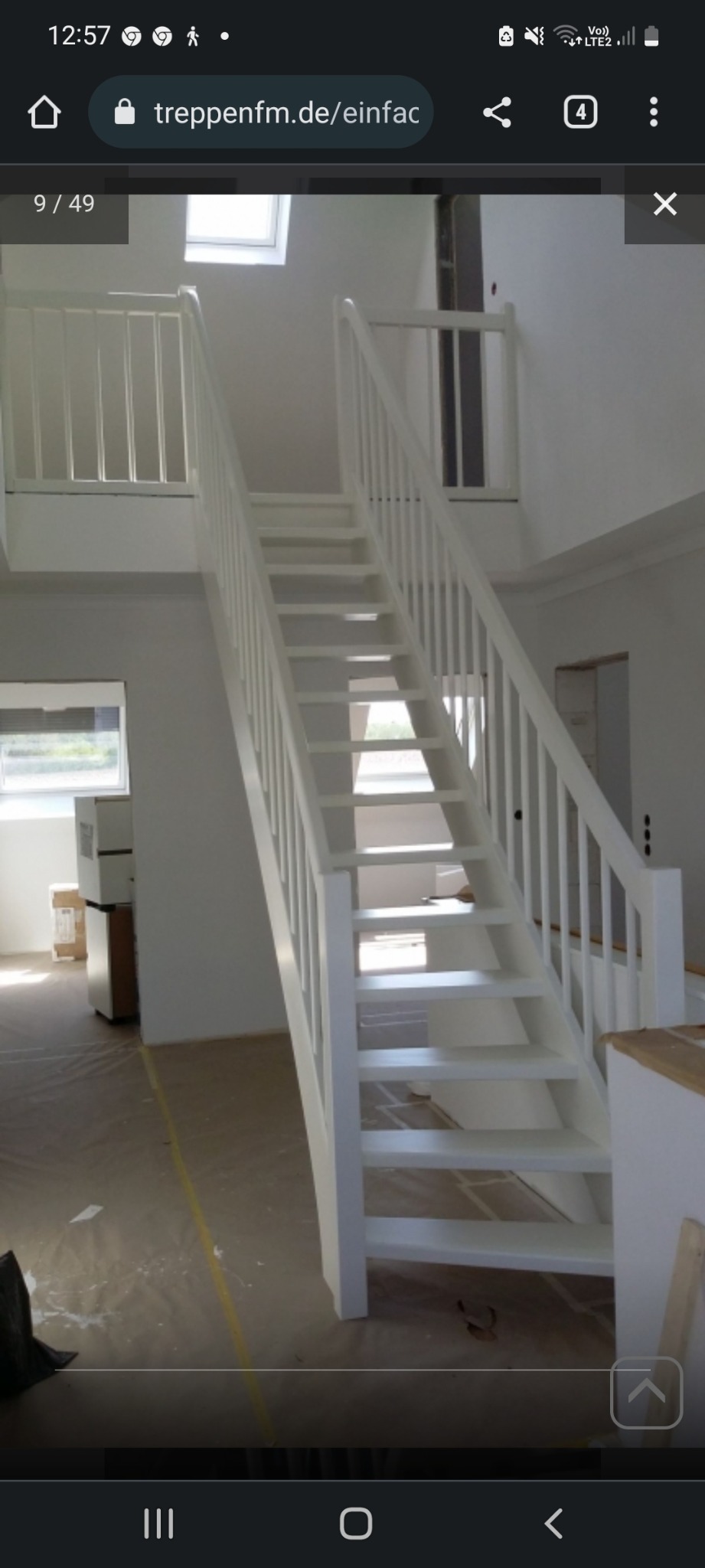 Białe, proste schody z drewnianymi stopniami i balustradą, prowadzące na antresolę w jasnym wnętrzu, widoczne zabezpieczenia podłogi folią malarską.