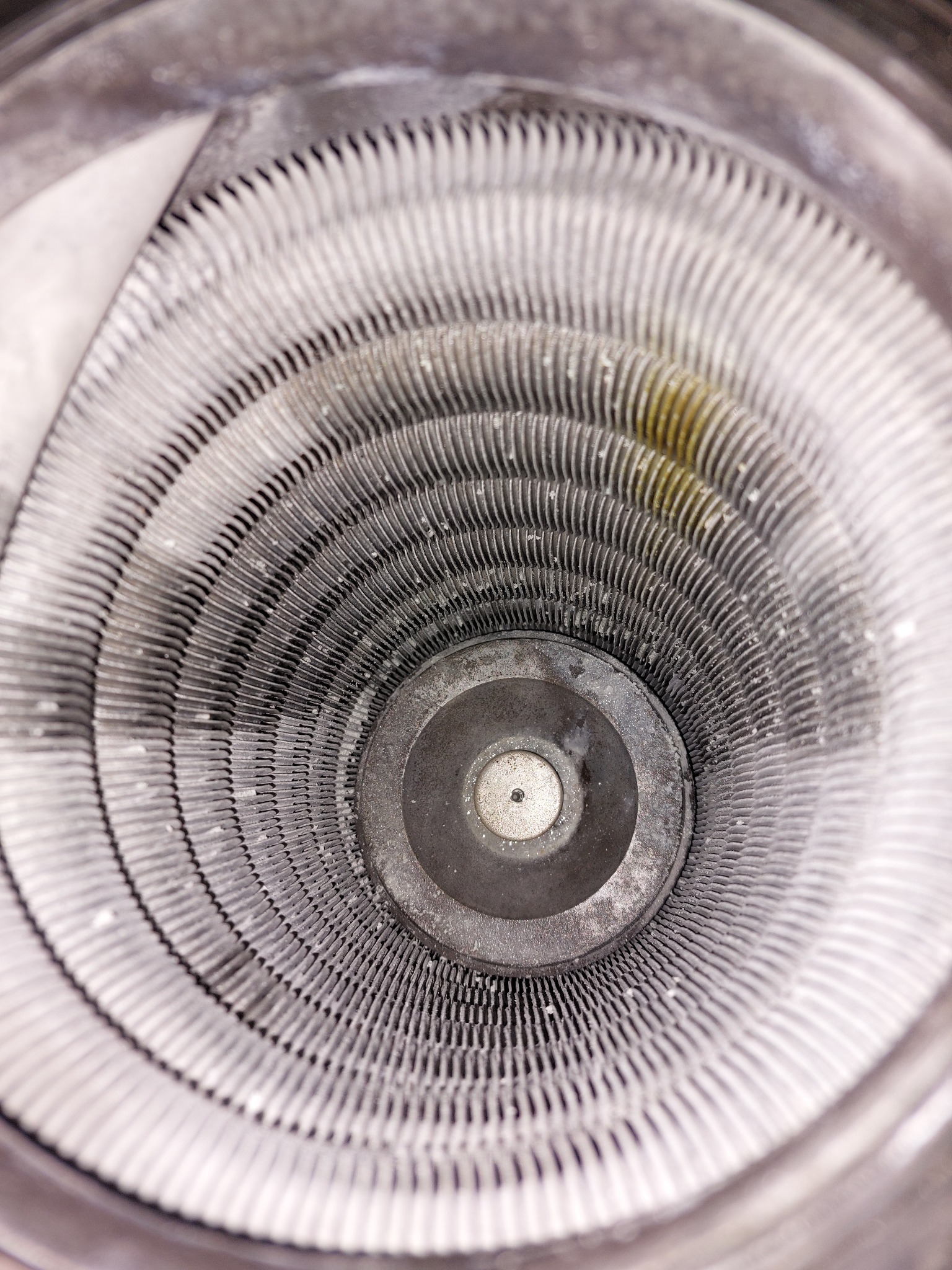 Wnętrze mocno zabrudzonego wymiennika ciepła z widocznymi żeberkami i śladami korozji oraz osadów, sfotografowane z bliska.