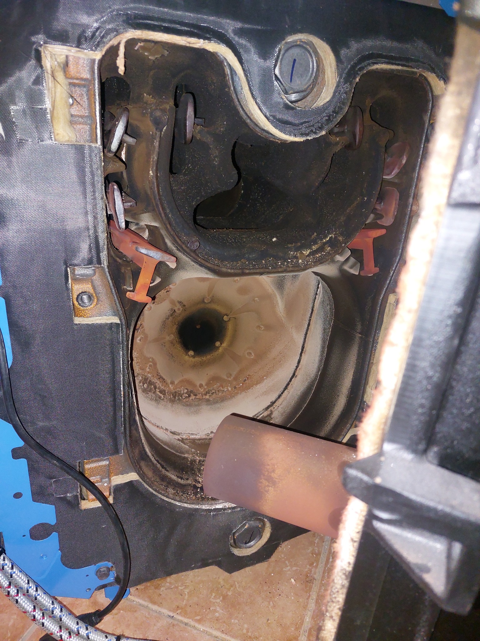 Wnętrze komory spalania pieca, widoczne elementy konstrukcyjne, osady i brud na ściankach, oraz fragment palnika.