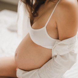 NATS PHOTOGRAPHY Natalia Głowacka - Kobieta w bieliźnie i rozpiętej koszuli obejmuje ciążowy brzuch, delikatne światło, neutralne tło.