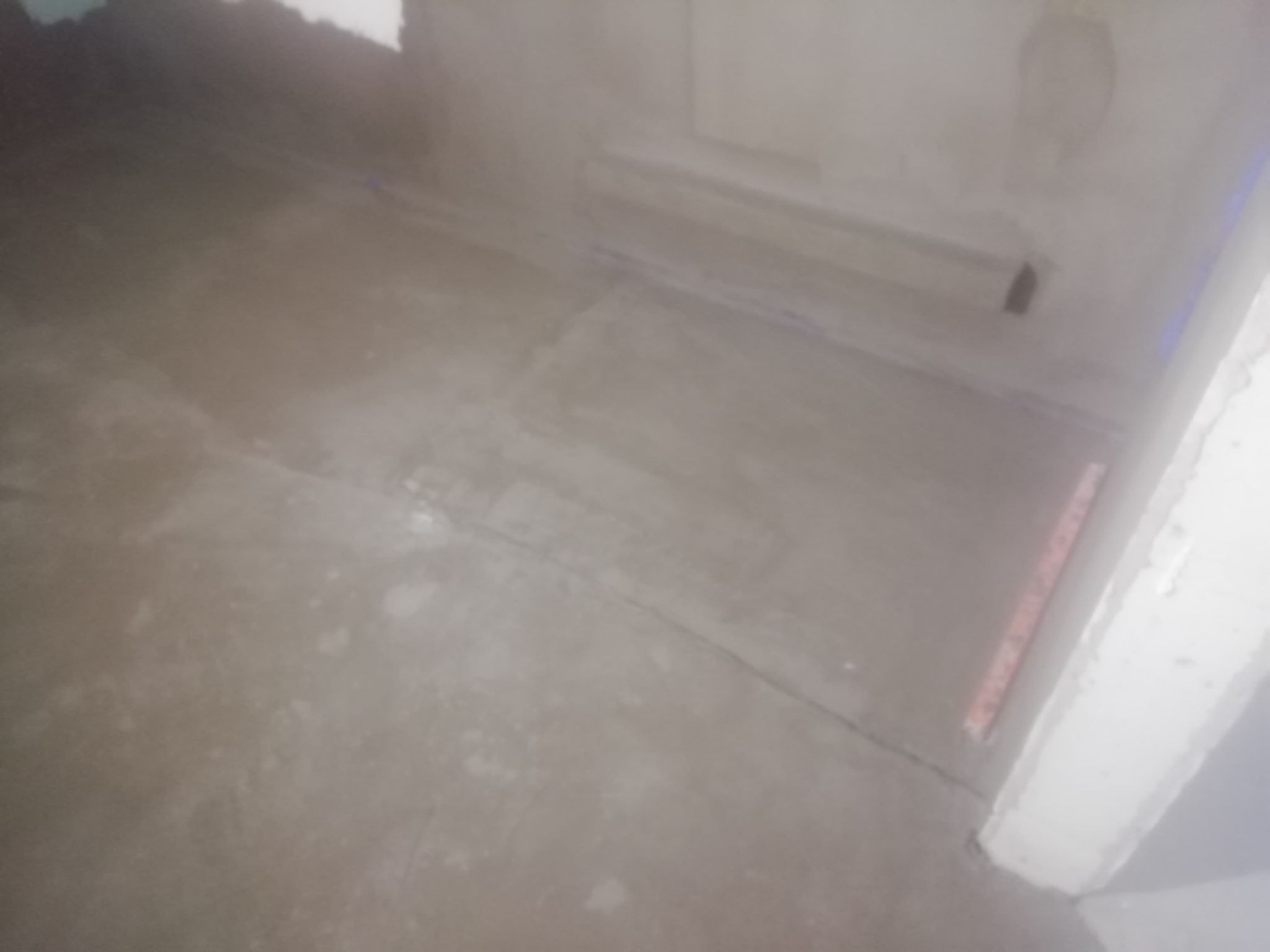 Przygotowanie podłoża pod posadzkę w Skierniewicach: wyrównana powierzchnia z widocznymi śladami po łatach i poziomicy przy ścianie.