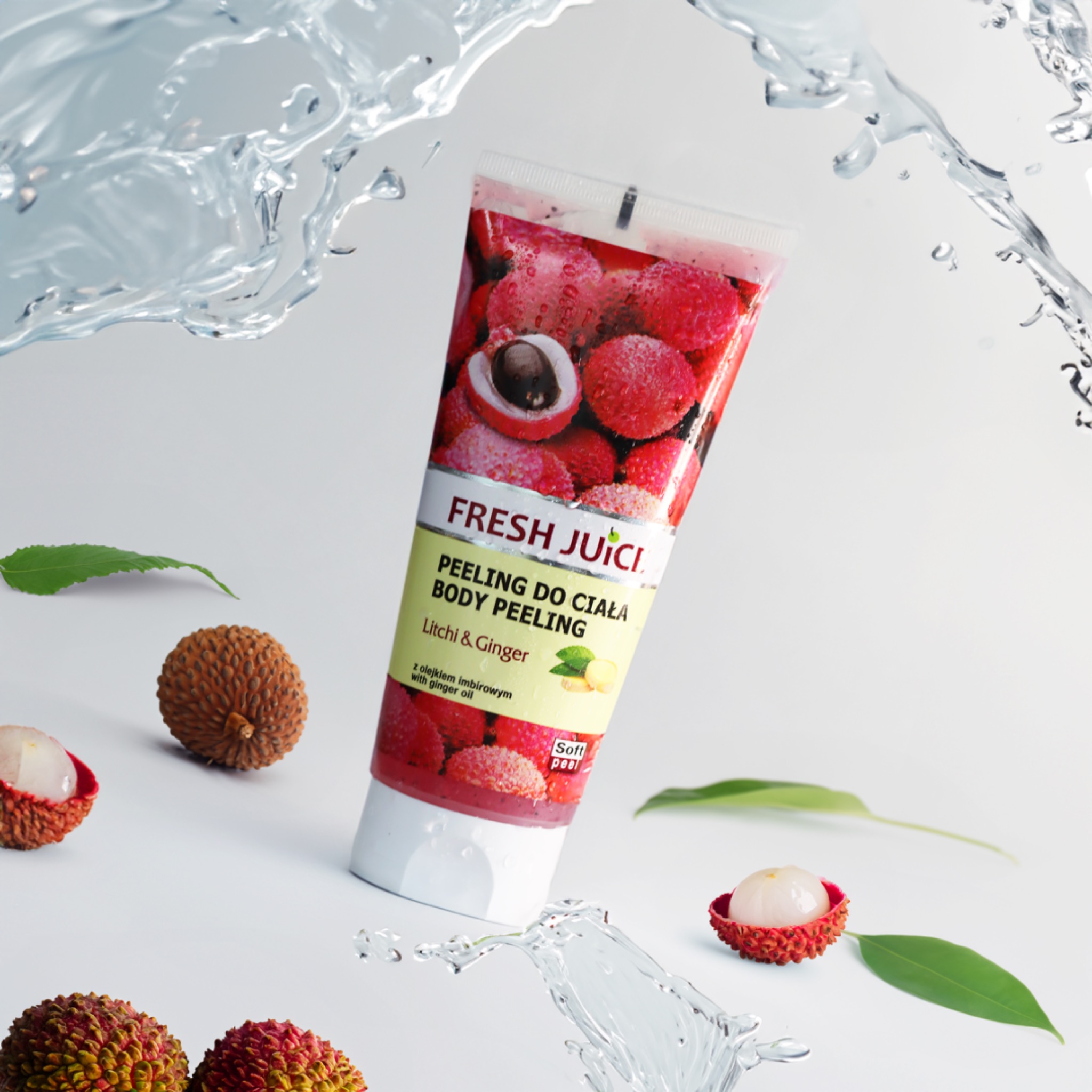 Tubka peelingu do ciała Fresh Juici o zapachu liczi i imbiru, otoczona świeżymi owocami liczi i rozpryskami wody na białym tle.