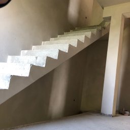 SuperTynk - Surowe betonowe schody w trakcie budowy w Żywcu, widoczne ściany przygotowane pod tynk.