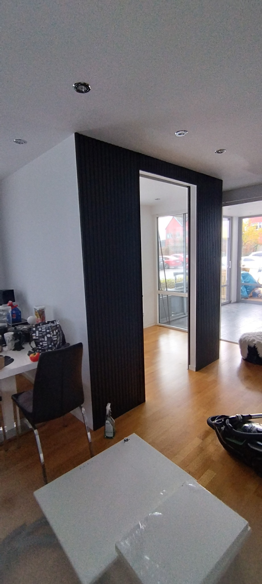 Nowoczesne wykończenie wnętrza z czarnymi panelami ściennymi tworzącymi przejście. Realizacja w Szumsku. Parkiet na podłodze, minimalistyczny design.