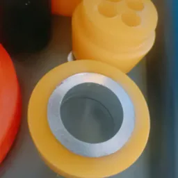 Żółte elementy z poliuretanu z metalowymi tulejami, różne kształty i rozmiary, prawdopodobnie elementy maszyn.