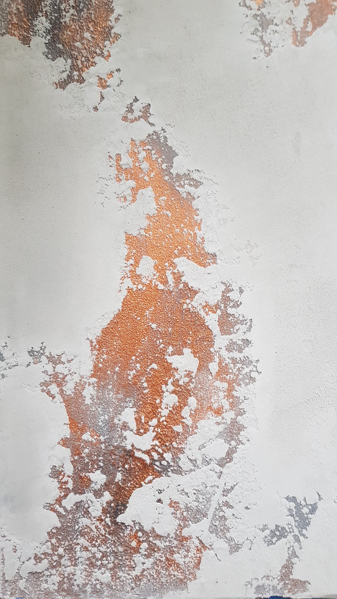 Dekoracyjna ściana z efektem miedzi i przetarć w odcieniach szarości na jasnym tle, ukazująca nieregularną teksturę.