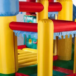 Dwie dziewczynki bawią się w kolorowym zamku dmuchanym z motywem Happy Bounce, jedna leży w dolnej części, druga siedzi na zjeżdżalni.