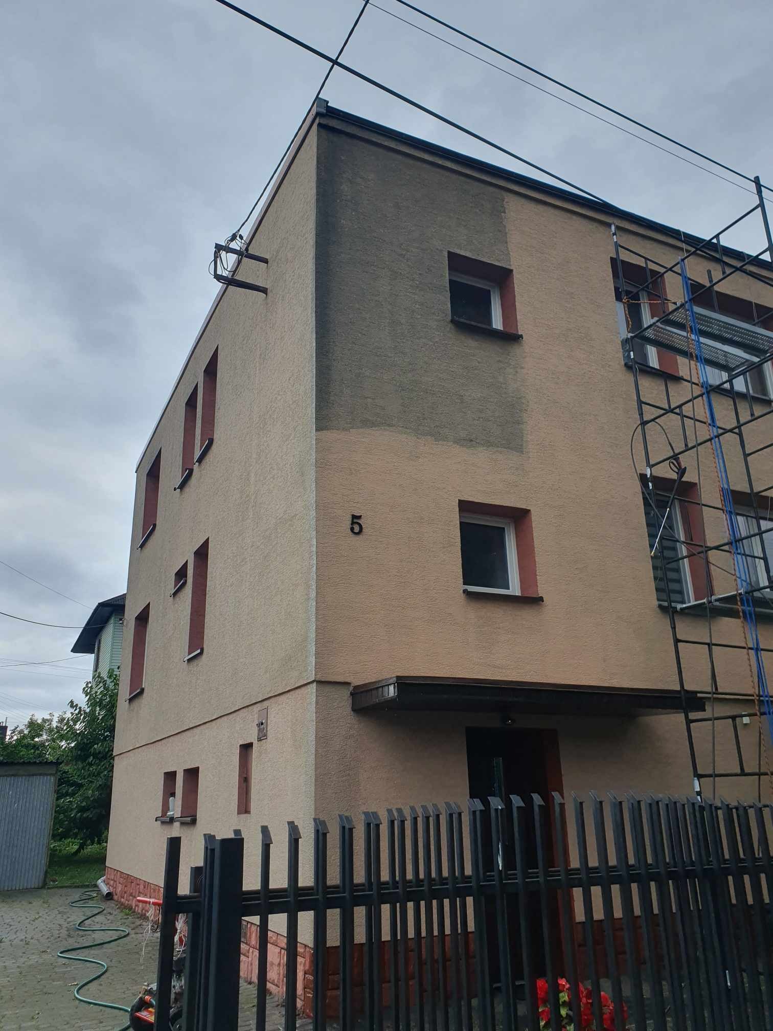 Fragment elewacji budynku z numerem '5' w trakcie czyszczenia, widoczne rusztowanie i różnica w kolorze elewacji przed i po czyszczeniu.