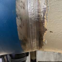 WELD SERVICE USŁUGI SPAWALNICZE - Spoina na rurze łączącej dwa odcinki, z widocznymi śladami po procesie łączenia i różnicą kolorów farby po obu stronach spoiny.