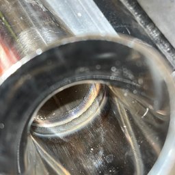 WELD SERVICE USŁUGI SPAWALNICZE - Wnętrze rury ze stali nierdzewnej z widocznym spoiwem po procesie łączenia, zamocowanej w uchwycie. Widoczne ślady obróbki i refleksy świetlne.