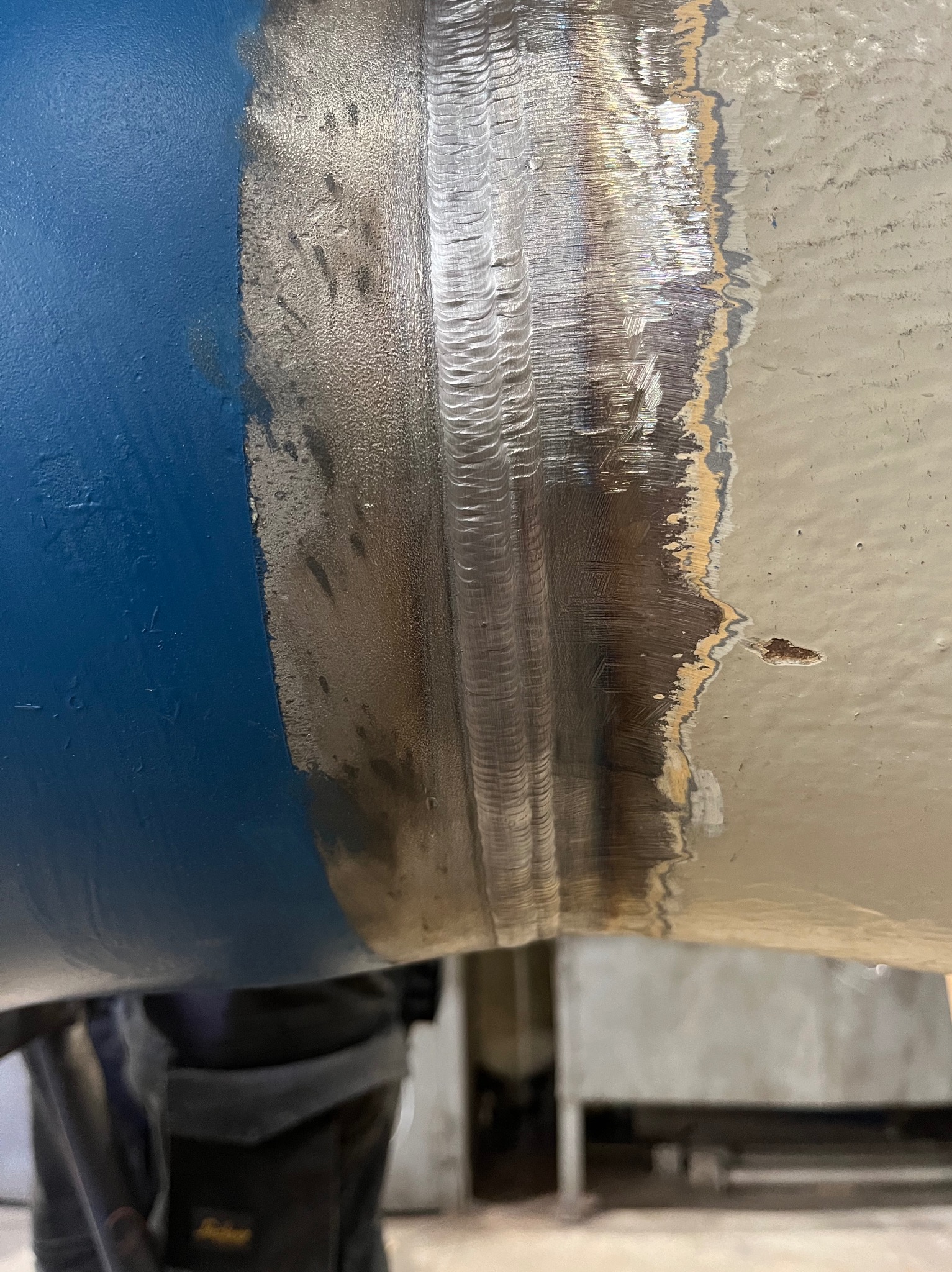 Spoina na rurze łączącej dwa odcinki, z widocznymi śladami po procesie łączenia i różnicą kolorów farby po obu stronach spoiny.