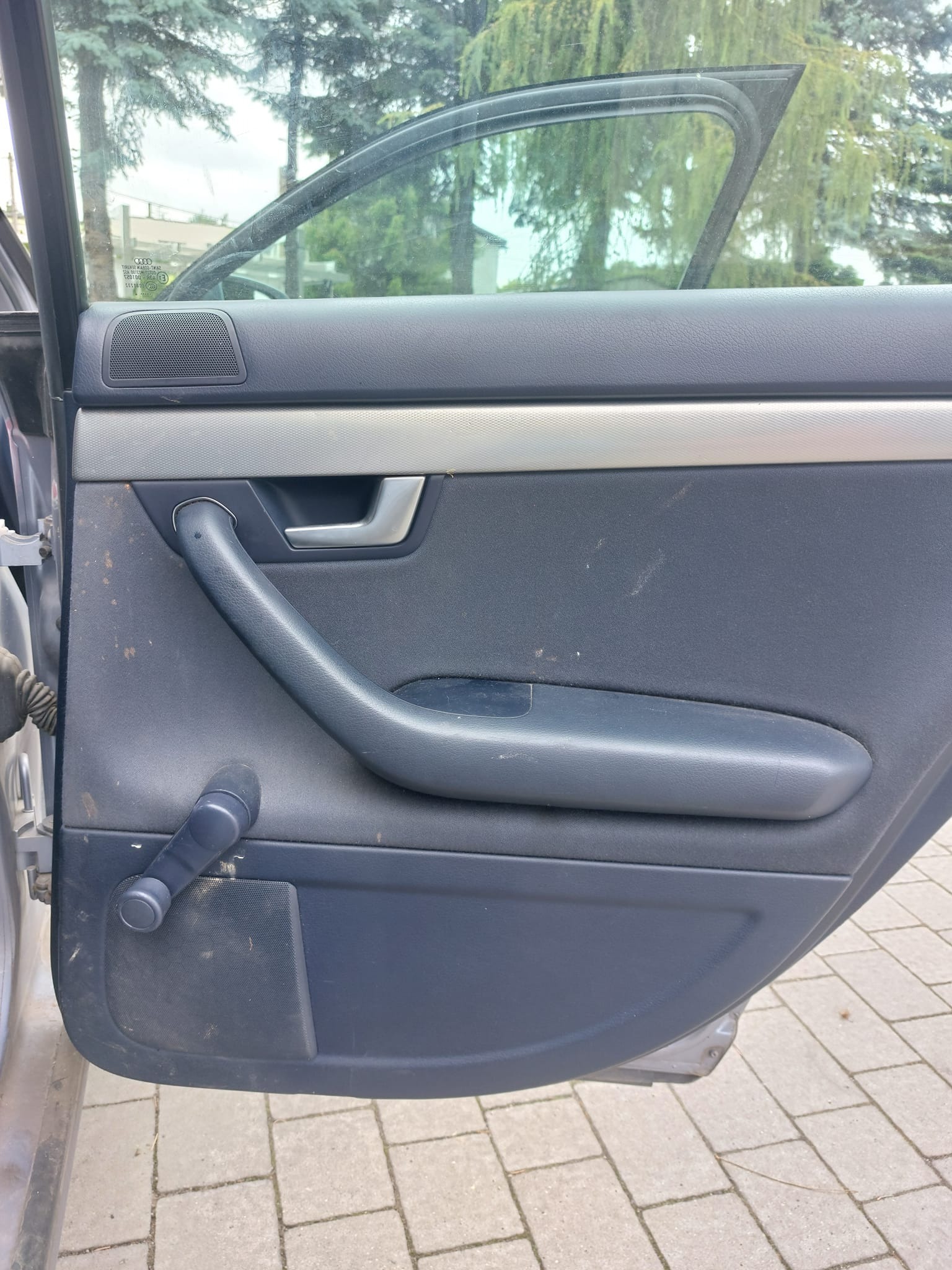 Brudna, granatowa tapicerka drzwi samochodu marki Audi, widoczne plamy i zabrudzenia na panelu.