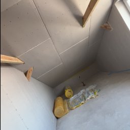 Usługi ogólnobudowlane - Montaż płyt gipsowych na poddaszu w Zawistach Podleśnych. Widoczne drewniane elementy konstrukcyjne i izolacja. Prace wykończeniowe w trakcie realizacji.