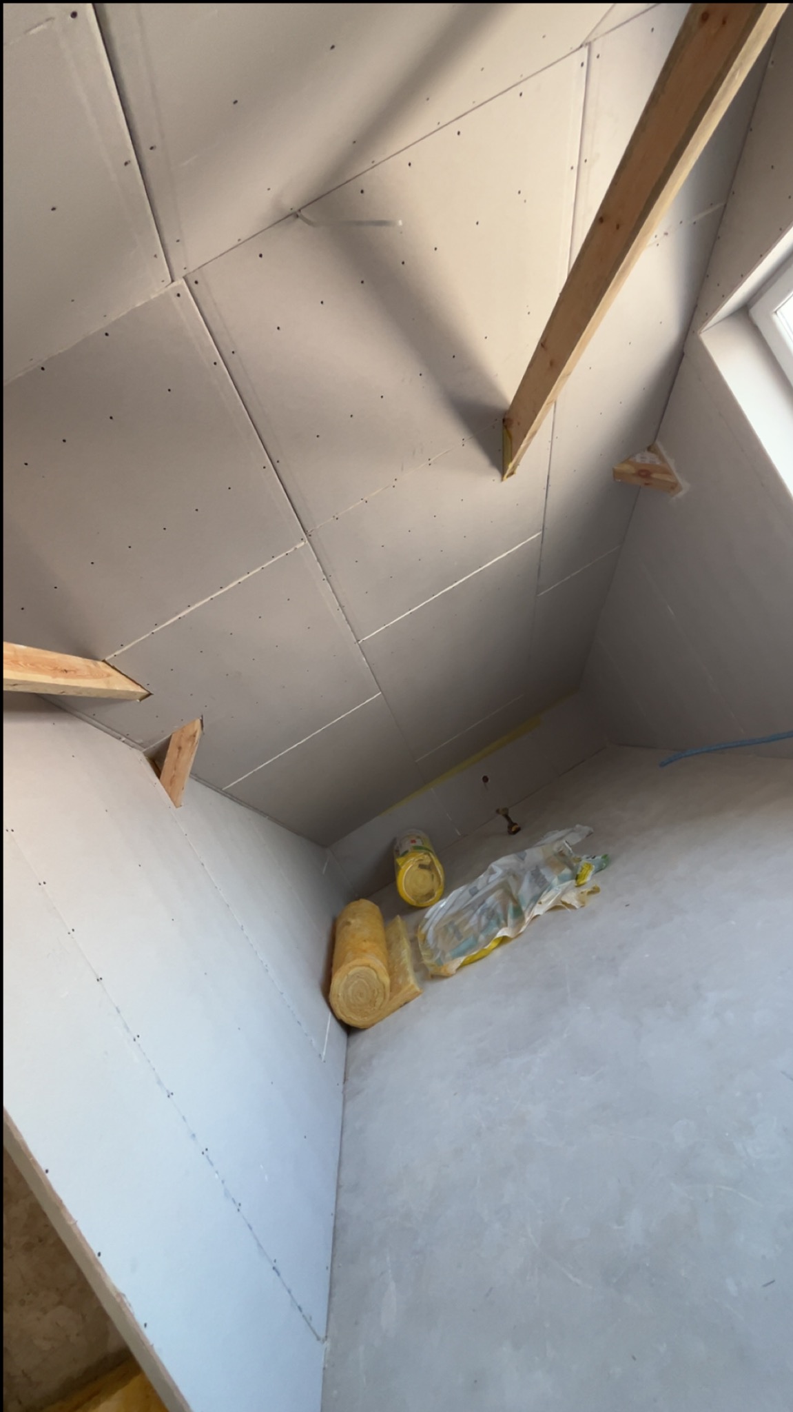 Montaż płyt gipsowych na poddaszu w Zawistach Podleśnych. Widoczne drewniane elementy konstrukcyjne i izolacja. Prace wykończeniowe w trakcie realizacji.