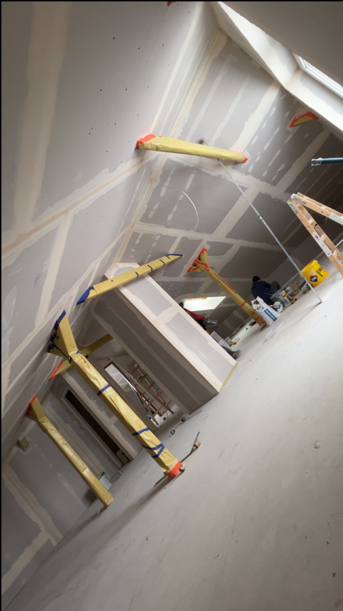 Skośne ujęcie poddasza z zamontowanymi płytami gipsowo-kartonowymi, widoczne profile i podpory montażowe. Prace wykończeniowe w trakcie realizacji.