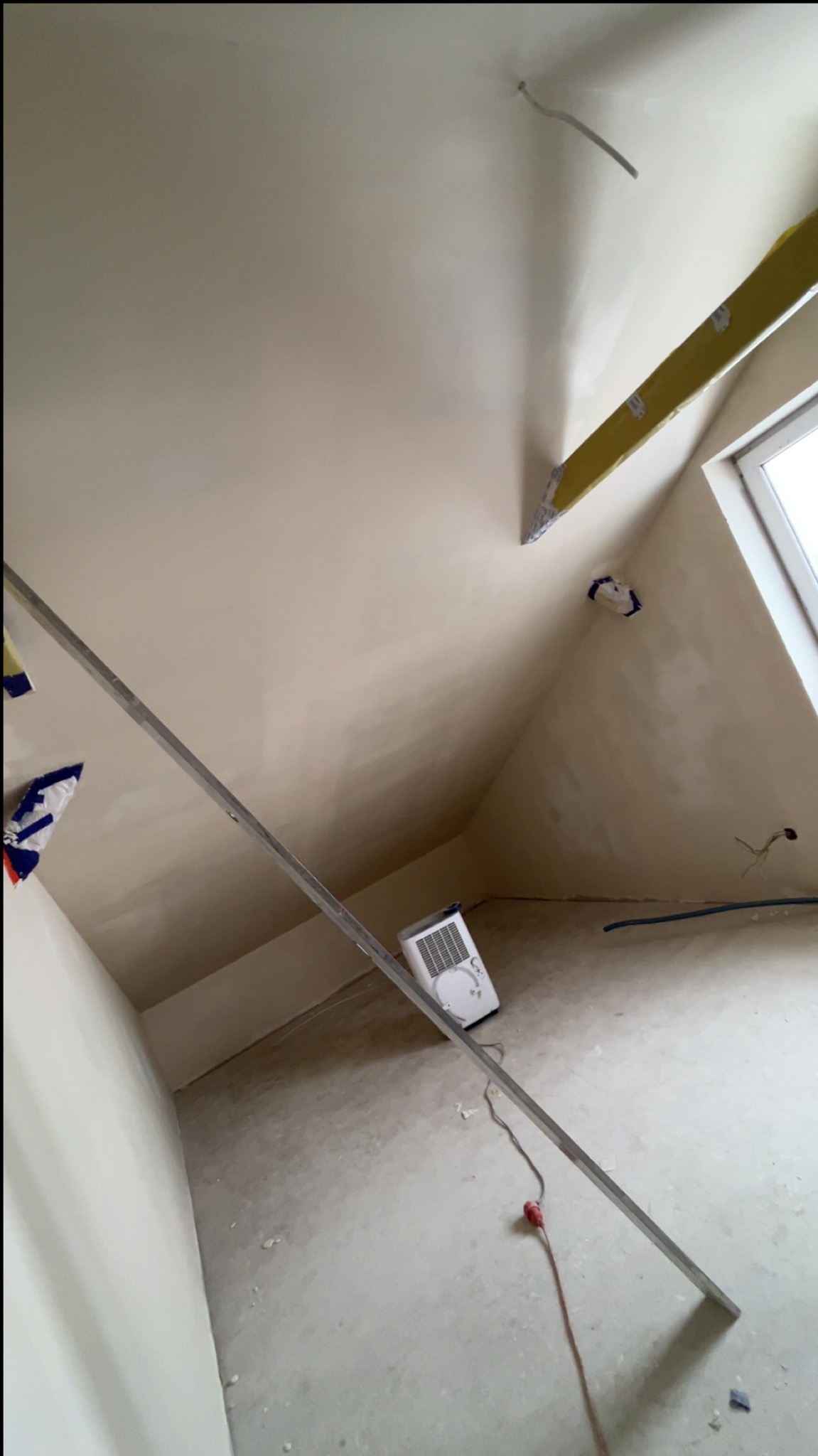 Poddasze po nałożeniu gładzi, widoczne narzędzia i poziomica. Ściany i sufit w jasnym odcieniu, przygotowane do dalszych prac wykończeniowych.