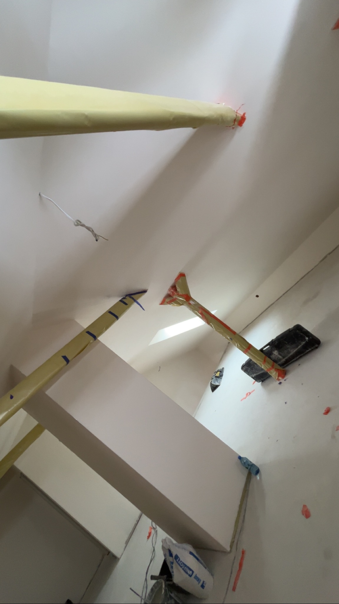 Sufit po montażu płyt, zabezpieczony taśmą malarską. Widoczne podpory i narzędzia, co sugeruje etap prac wykończeniowych w pomieszczeniu.