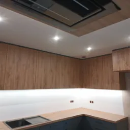 Nowoczesna kuchnia z drewnianymi szafkami górnymi, szarymi szafkami dolnymi i oświetleniem LED pod szafkami. Widoczne gniazdka elektryczne na ścianie.