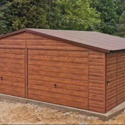 Gotowy garaż blaszany w kolorze drewnopodobnym z dwoma bramami, na betonowej wylewce, na tle zieleni.