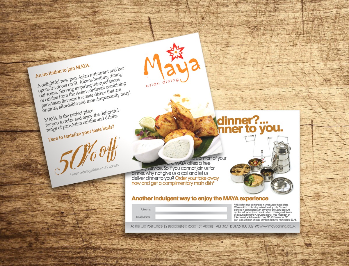 Dwie ulotki restauracji azjatyckiej Maya z informacjami o ofercie, zniżkach i adresie, leżące na drewnianym stole.