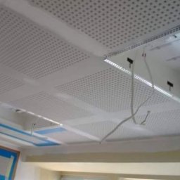 Zal - Bud - Sufit podwieszany z płyt perforowanych w trakcie montażu, widoczne przewody i elementy konstrukcyjne.