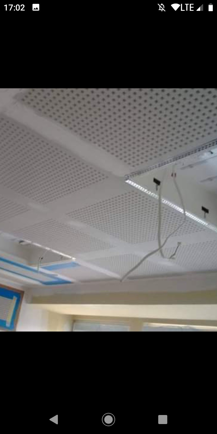 Sufit podwieszany z płyt perforowanych w trakcie montażu, widoczne przewody i elementy konstrukcyjne.