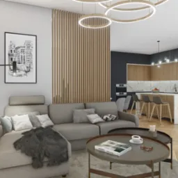 Wizualizacja salonu z kominkiem, sofą narożną i otwartą kuchnią z wyspą, oświetlonego nowoczesnymi lampami pierścieniowymi. Na stoliku kawowym książka i filiżanka.