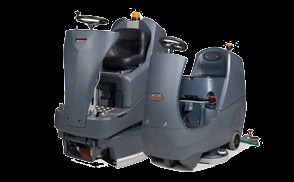 Dwie szorowarki samojezdne w Łodzi, jedna z fotelem operatora, druga mniejsza, bez fotela, obie w szarym kolorze, na białym tle.