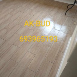 AK-BUD - Ułożona podłoga z płytek imitujących drewno w jasnym odcieniu, z widocznym logo AK-BUD i numerem telefonu 693965193 nałożonym na zdjęcie.